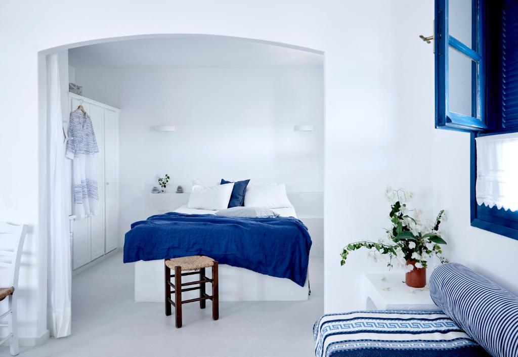biała sypialnia z niebieskim łóżkiem i stołkiem w obiekcie Villa Ippocampi - Adults Only w mieście Hersonissos