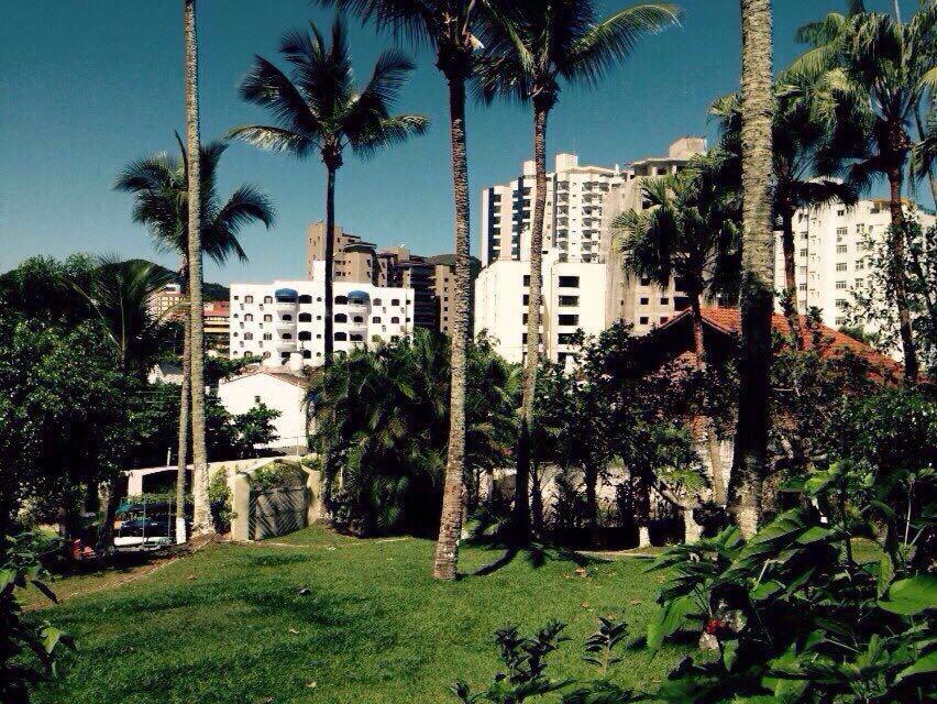un parc avec des palmiers en face d'une ville dans l'établissement Coqueiros Praia Martin de Sá, à Caraguatatuba