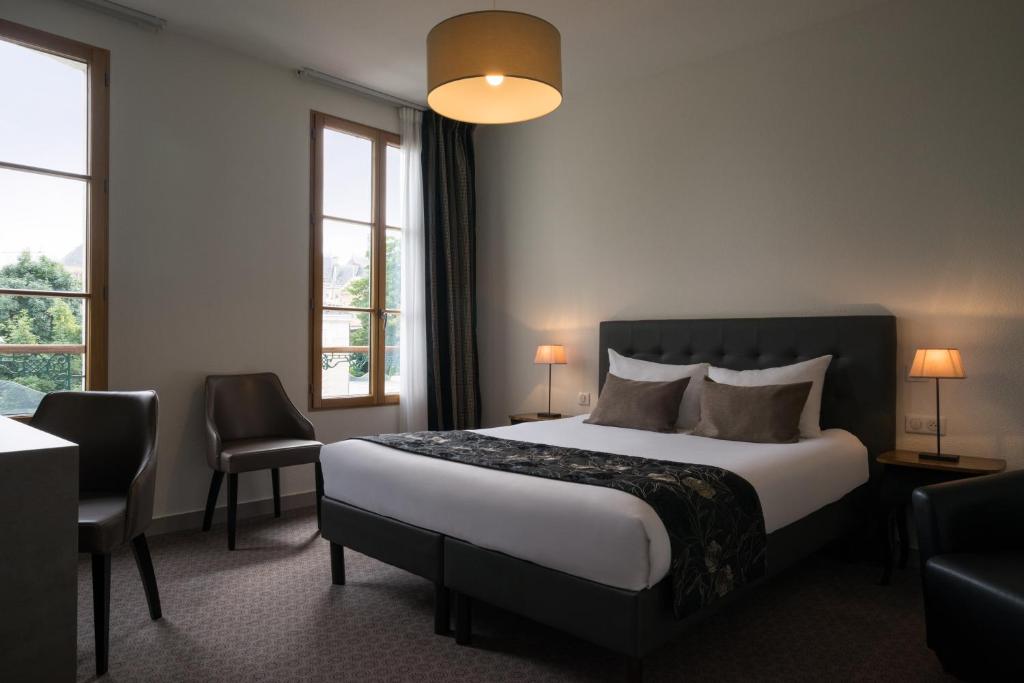 a hotel room with a bed and two windows at Hôtel du Moulin in Niort