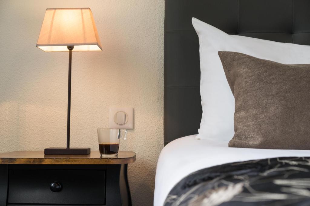 a lamp on a night stand next to a bed at Hôtel du Moulin in Niort