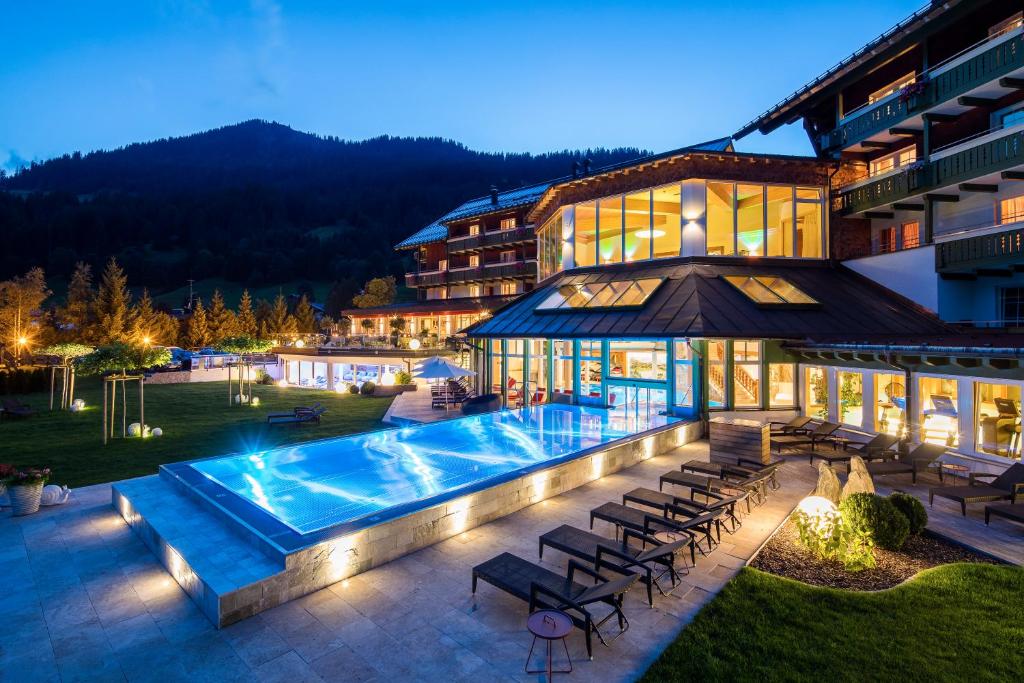 a hotel with a swimming pool in front of a building at Haller's Geniesserhotel in Mittelberg