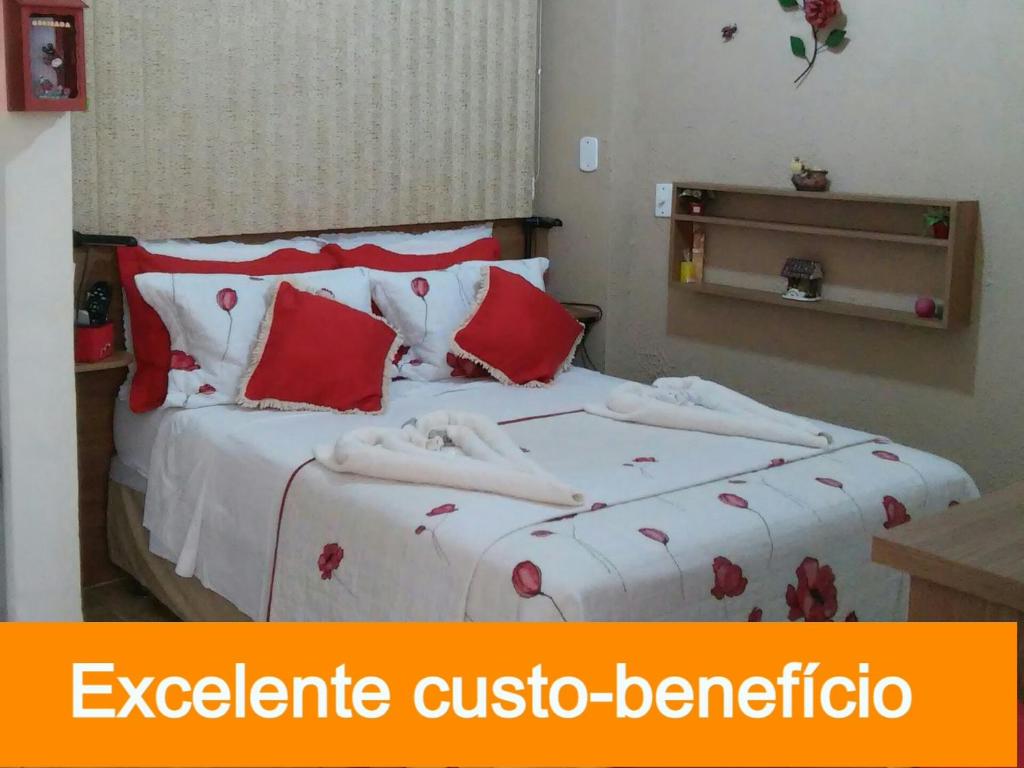 um quarto com uma cama com lençóis vermelhos e brancos em Apart Hotel em Caxambu207 em Caxambu