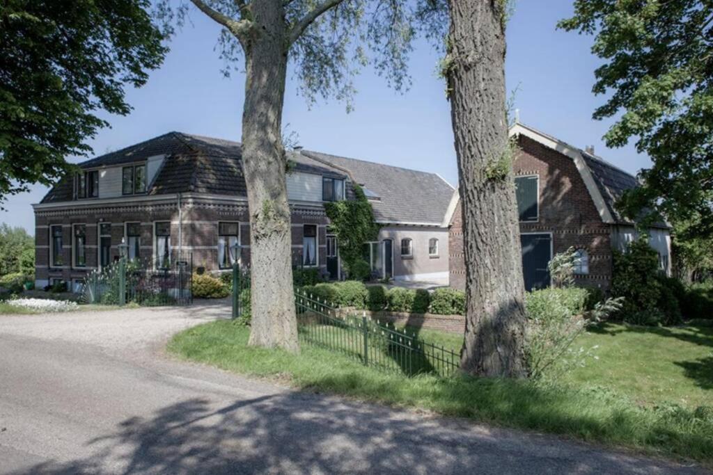 una casa grande con dos árboles delante de ella en Landelijk appartement in een mooi recreatiegebied en Abcoude