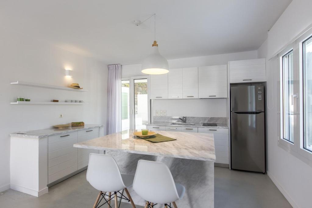 a kitchen with white cabinets and a stainless steel refrigerator at Minimal Apartment with a swimming pool and sea view in Koundouros in Koundouros