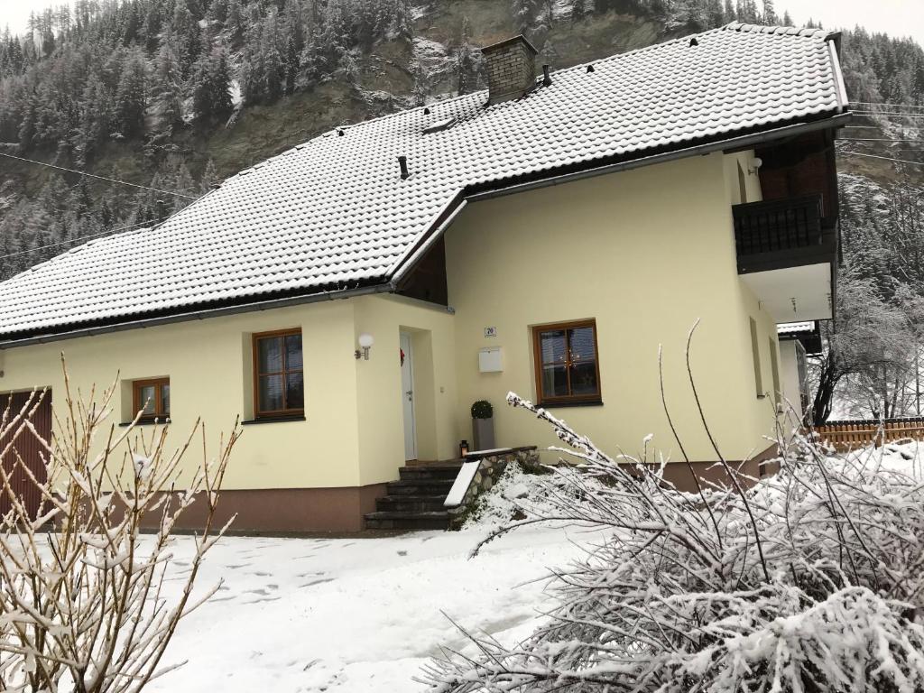 a yellow house with snow on the ground at Haus Bayliss in Zederhaus