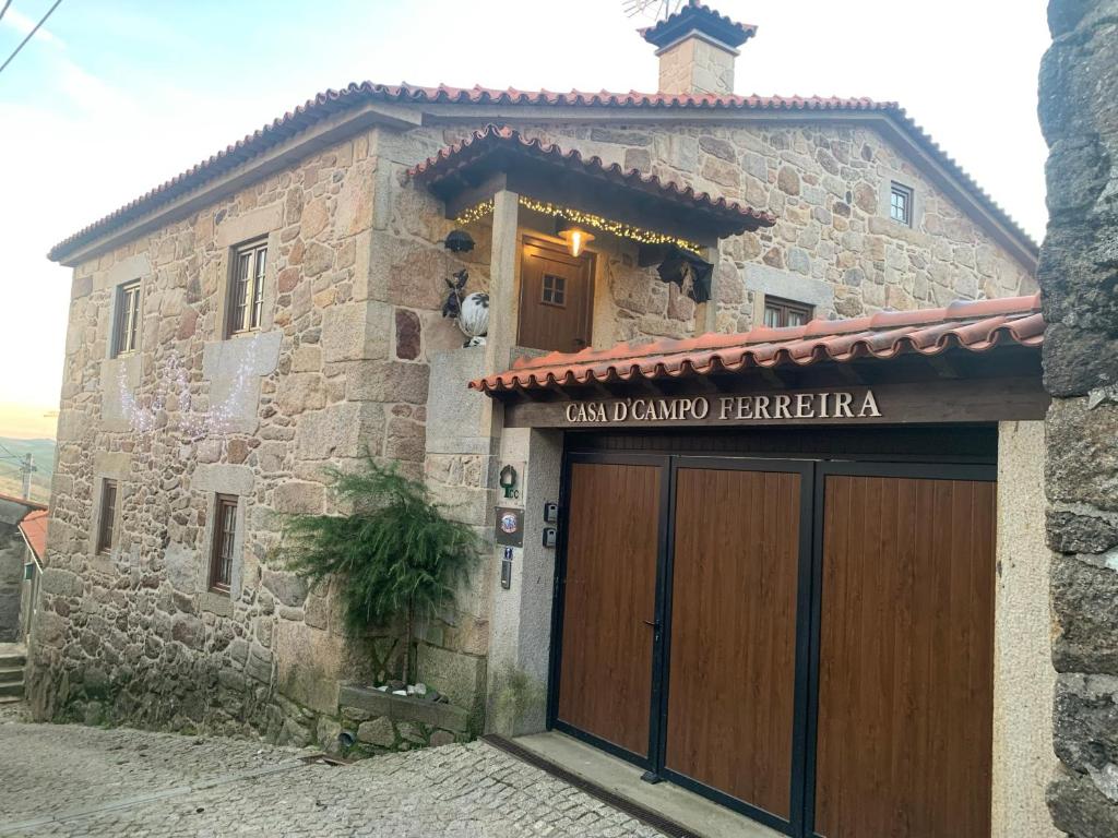 a stone building with a large wooden garage door at Casa D'Campo Ferreira in Pitões das Júnias