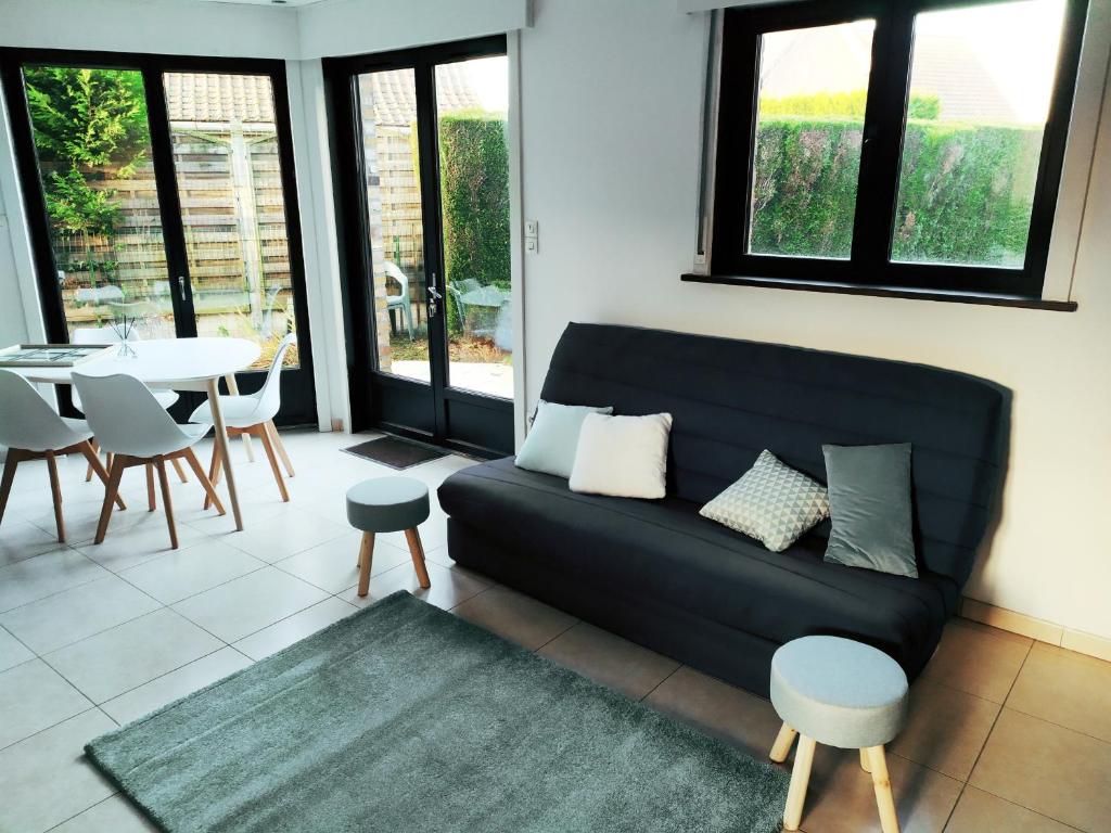 een woonkamer met een zwarte bank en een tafel bij Maison familiale tout confort avec garage in Lompret