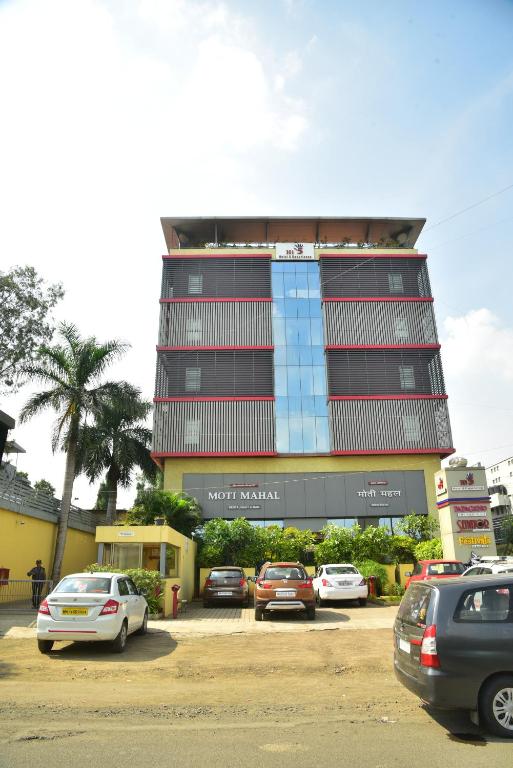 a tall building with cars parked in a parking lot at Hi 5 Hotel & Experience in Nashik