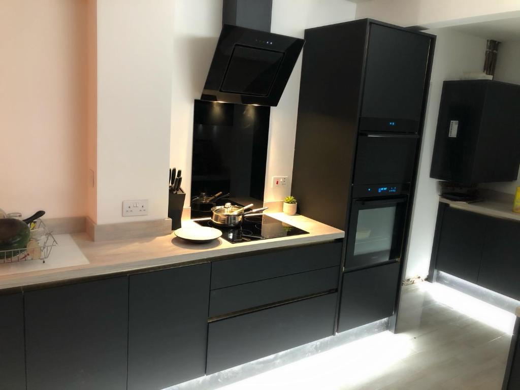 een keuken met zwarte kasten en een fornuis met oven bij Spacious double bedrooms sharing new bathroom, en-suite option available, Kings Lynn in Kings Lynn