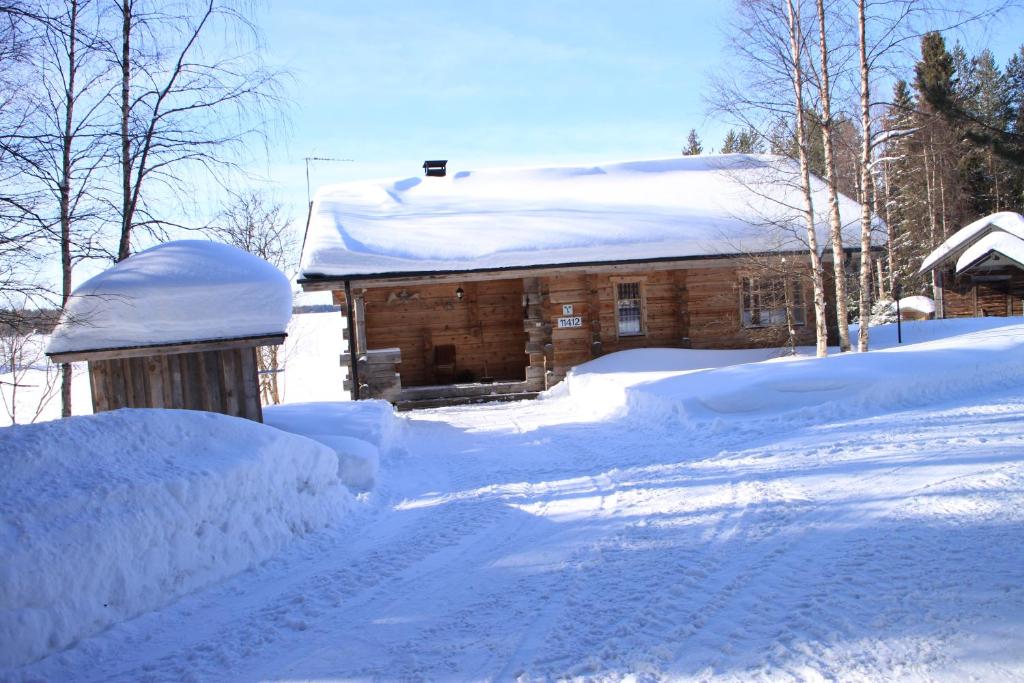a snow covered house with a pile of snow at Niemen Lomat in Kuusamo