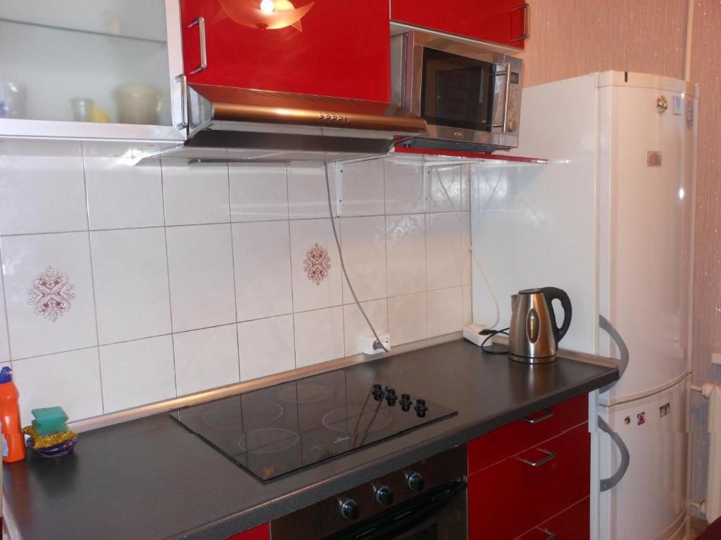 a kitchen with red cabinets and a black counter top at Apartaments LiS 2 in Petergof