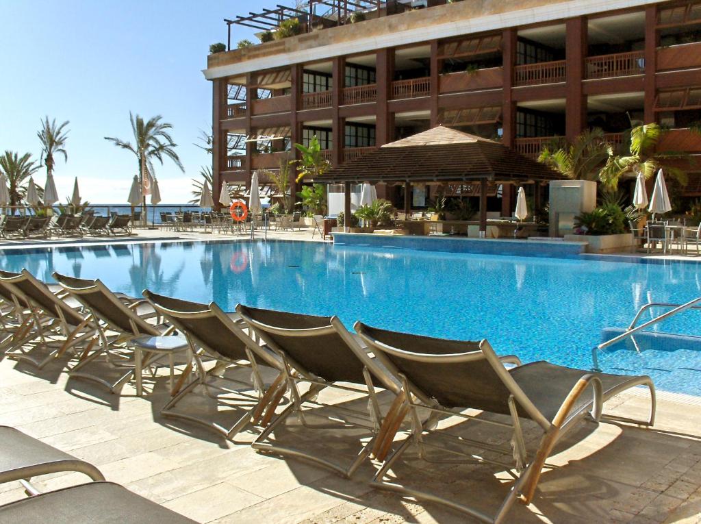 a swimming pool with chairs in front of a building at Gran Hotel Guadalpín Banus in Marbella