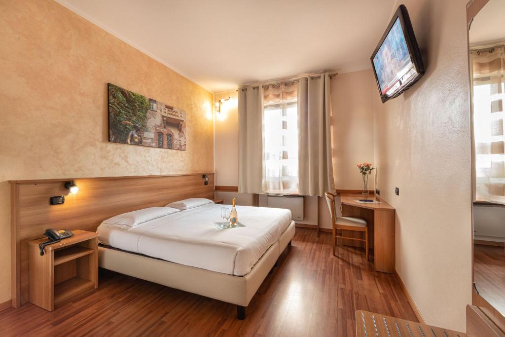 ドッソブオノにあるHotel Postumiaのベッド1台、壁掛けテレビが備わるホテルルームです。