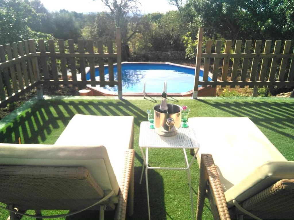 un patio trasero con 2 sillas, una mesa y una piscina en SWEET HOUSE, en Santa Margalida