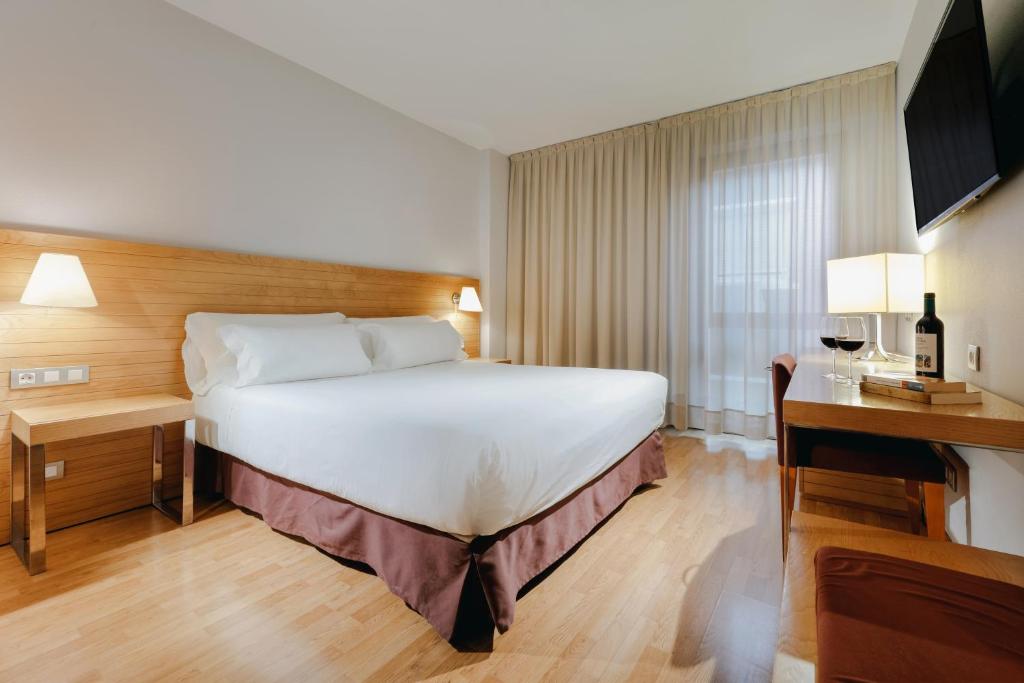 um quarto de hotel com uma cama grande e uma secretária em Hesperia Zaragoza Centro em Zaragoza