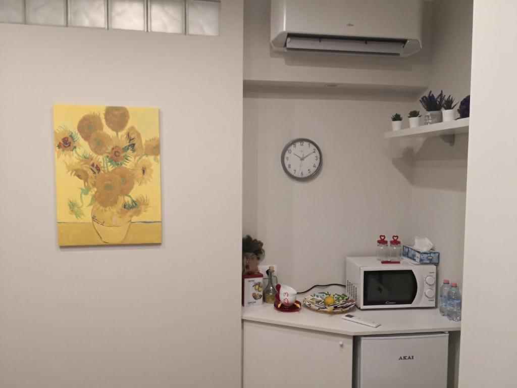 a kitchen with a microwave and a clock on the wall at Pontassieve Guest House centro storico camera con bagno 20 minuti da Firenze in Pontassieve