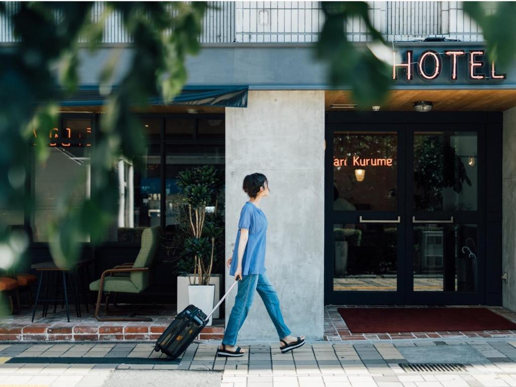 un hombre caminando por una calle con una maleta en Hostel ilfaro Kurume, en Kurume