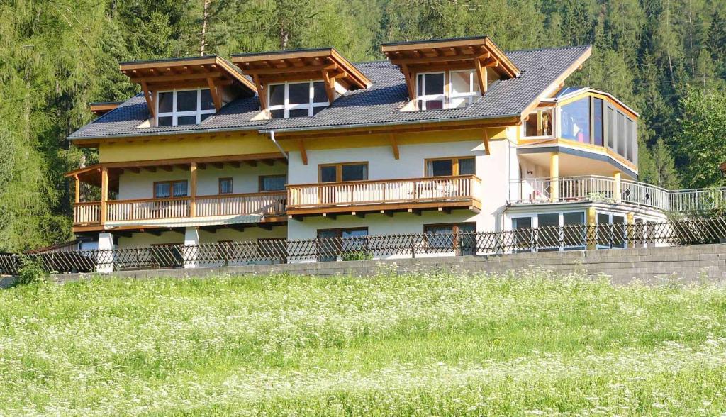 una casa grande en una colina con un campo en Gästehaus Falkenblick, en Arzl im Pitztal