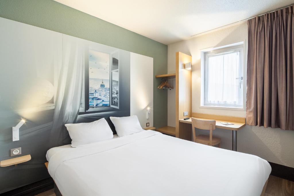 サン・ミシェル・シュル・オルジュにあるB&B HOTEL Saint-Michel sur Orgeの大きなベッドと窓が備わるホテルルームです。