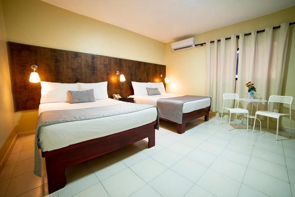 um quarto de hotel com duas camas e uma mesa em Hotel Real Bella Vista em Santo Domingo