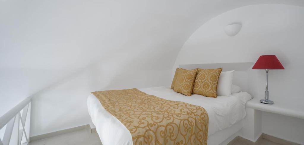 a bedroom with a bed and a table with a lamp at Above Blue Suites in Imerovigli