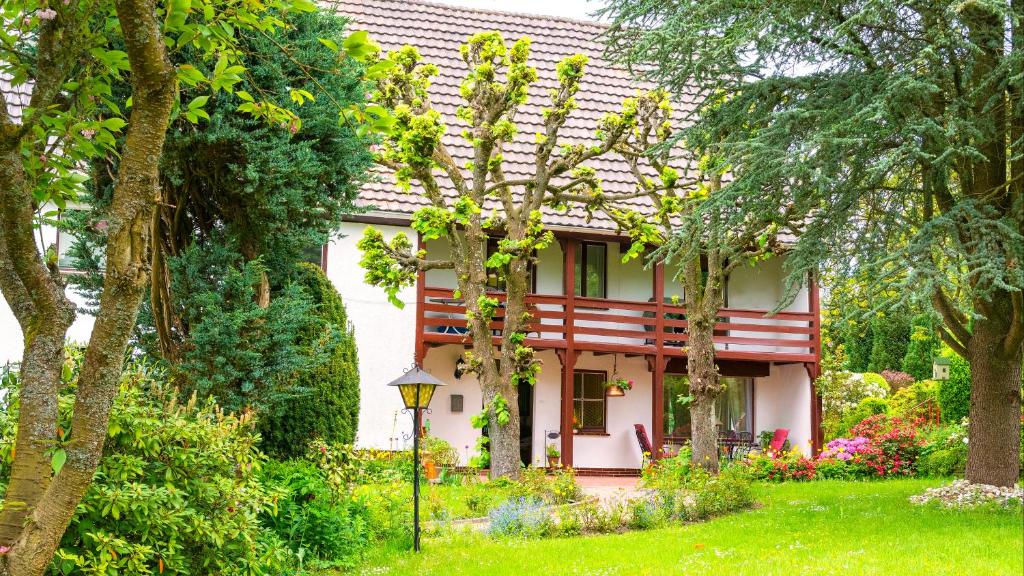 une maison blanche avec un jardin et des arbres dans l'établissement Hoffmanns-Hof-Sinspert, à Reichshof 