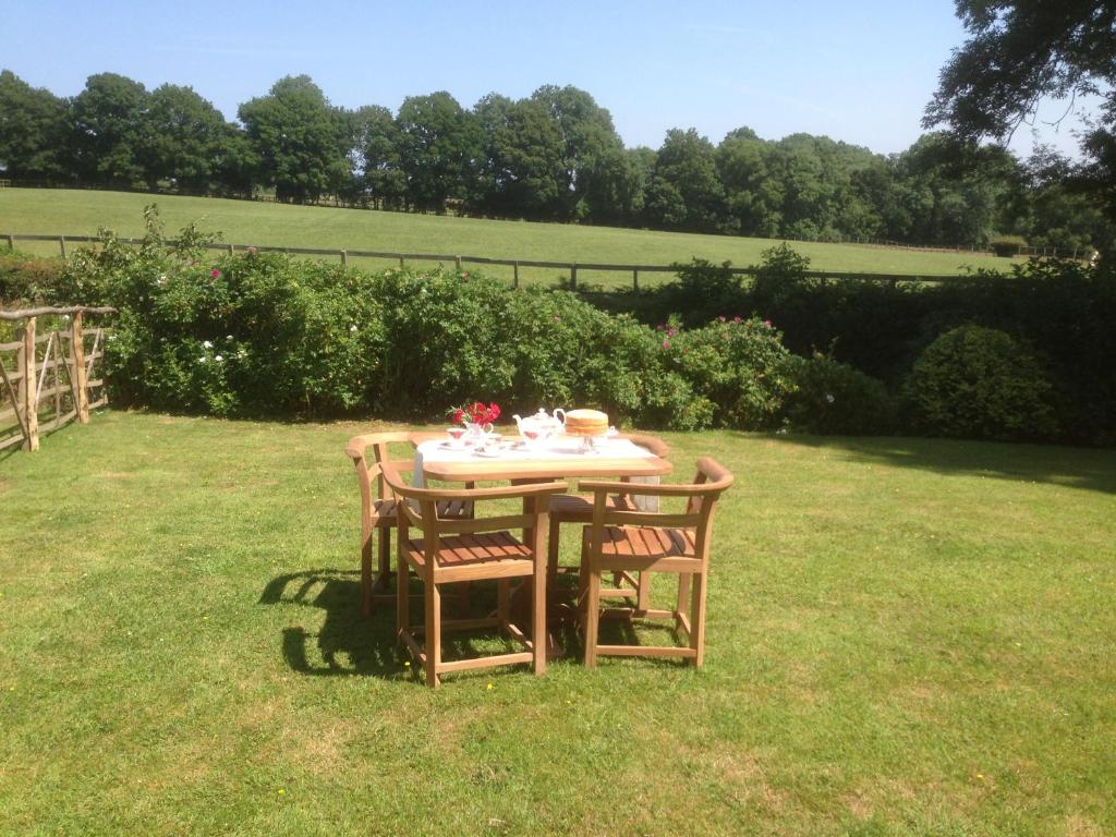 une table avec des chaises assises dans l'herbe dans l'établissement Snaffles, à Royal Tunbridge Wells