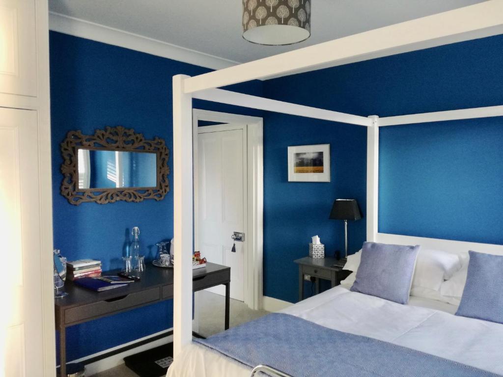 a bedroom with blue walls and a bed and a mirror at Number 8 Cheltenham in Cheltenham