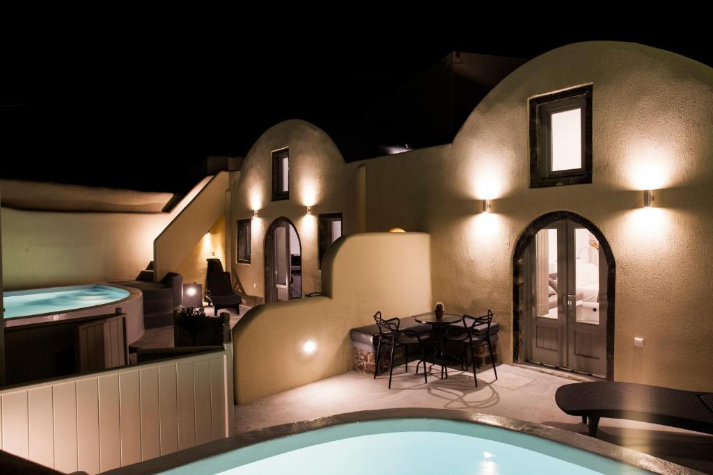 a house with a swimming pool and a dining room at Cupola Suites in Oia