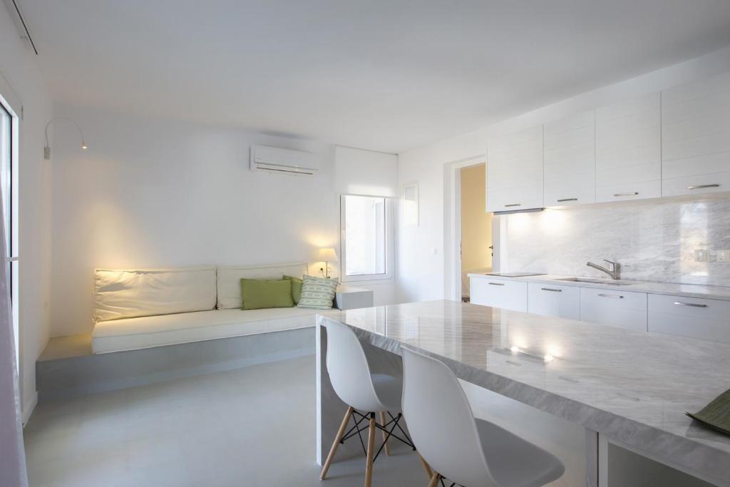 a white kitchen with white cabinets and a table and chairs at 67sq meters modern apartment with a swimming pool and sea view in Koundouros in Koundouros