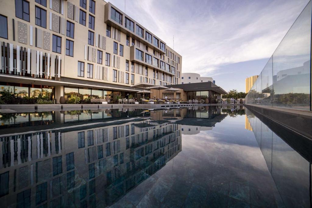 a building with a reflection in a pool of water at Noom Hotel Niamey in Niamey