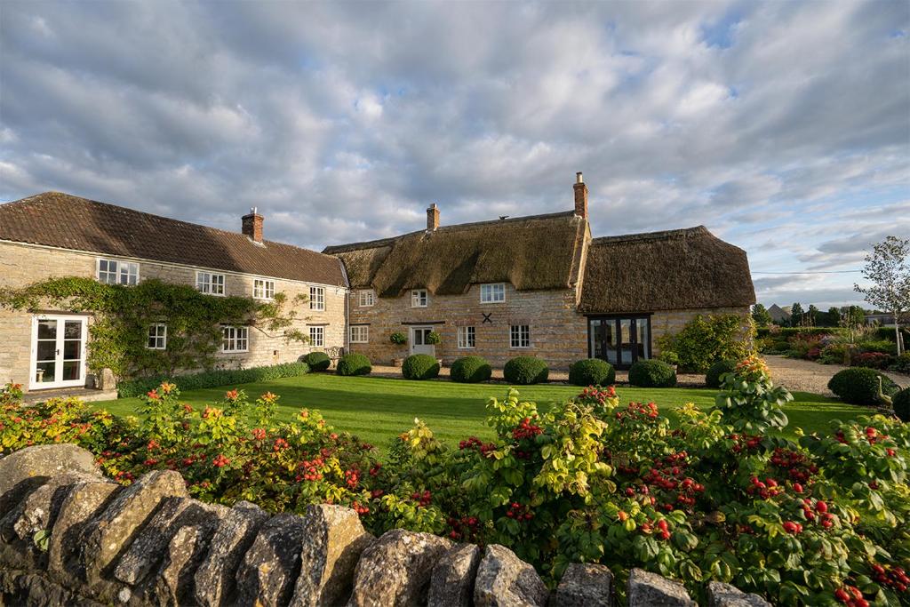 a large house with a stone fence and flowers at Middle Farm House in Shepton Mallet