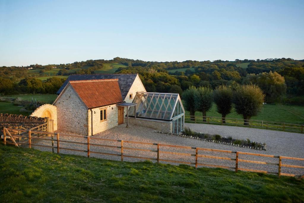 a small house with a greenhouse in a field at Goose Run Cottage in Corscombe