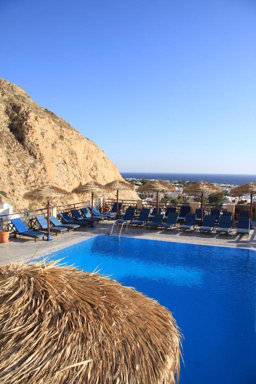 una gran piscina con sillas y techo de paja en Aegean View Hotel, en Kamari
