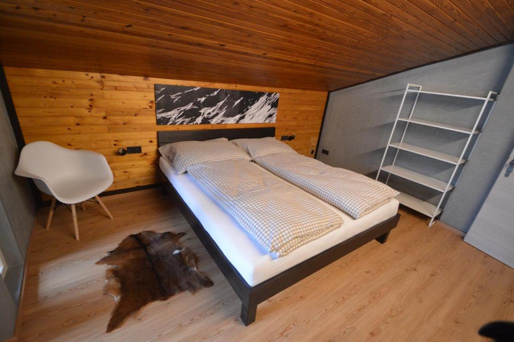 sypialnia z łóżkiem, drabiną i krzesłem w obiekcie Bergchalet Hinterstoder w mieście Hinterstoder