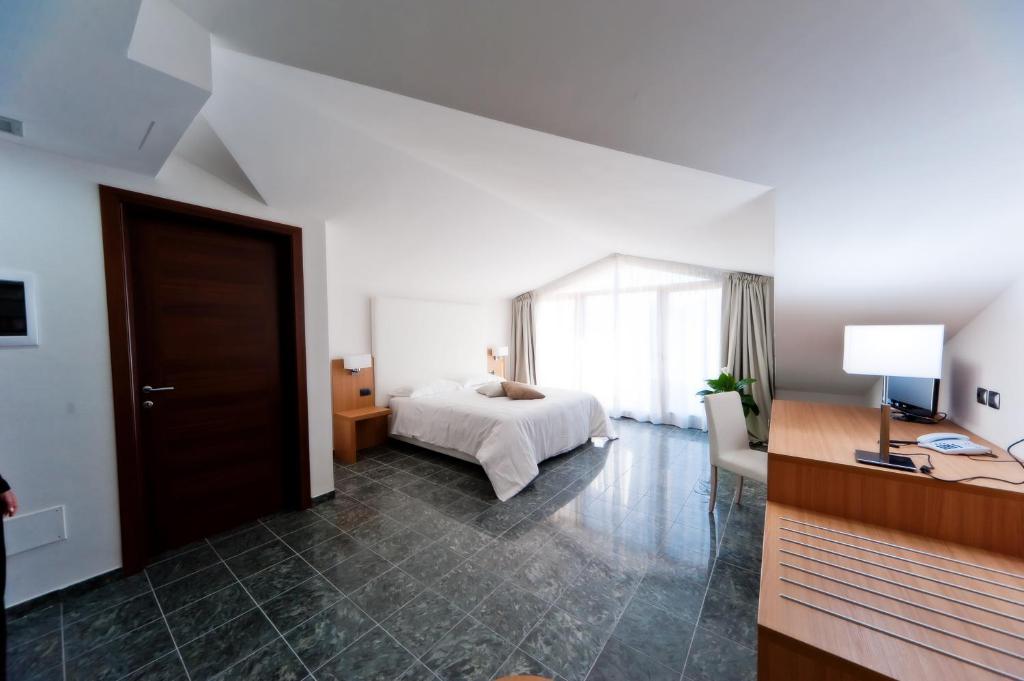 een witte slaapkamer met een bed en een raam bij Vea Resort Hotel in Mercato San Severino