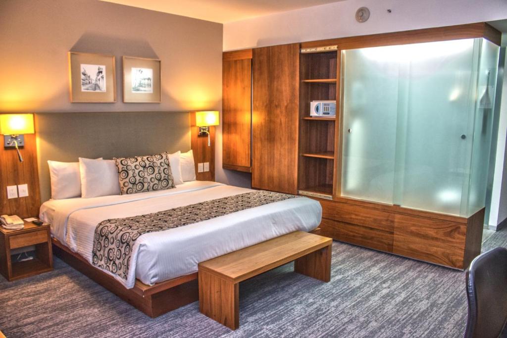 una camera d'albergo con letto e doccia in vetro di Casa Inn Premium Hotel Queretaro a Querétaro