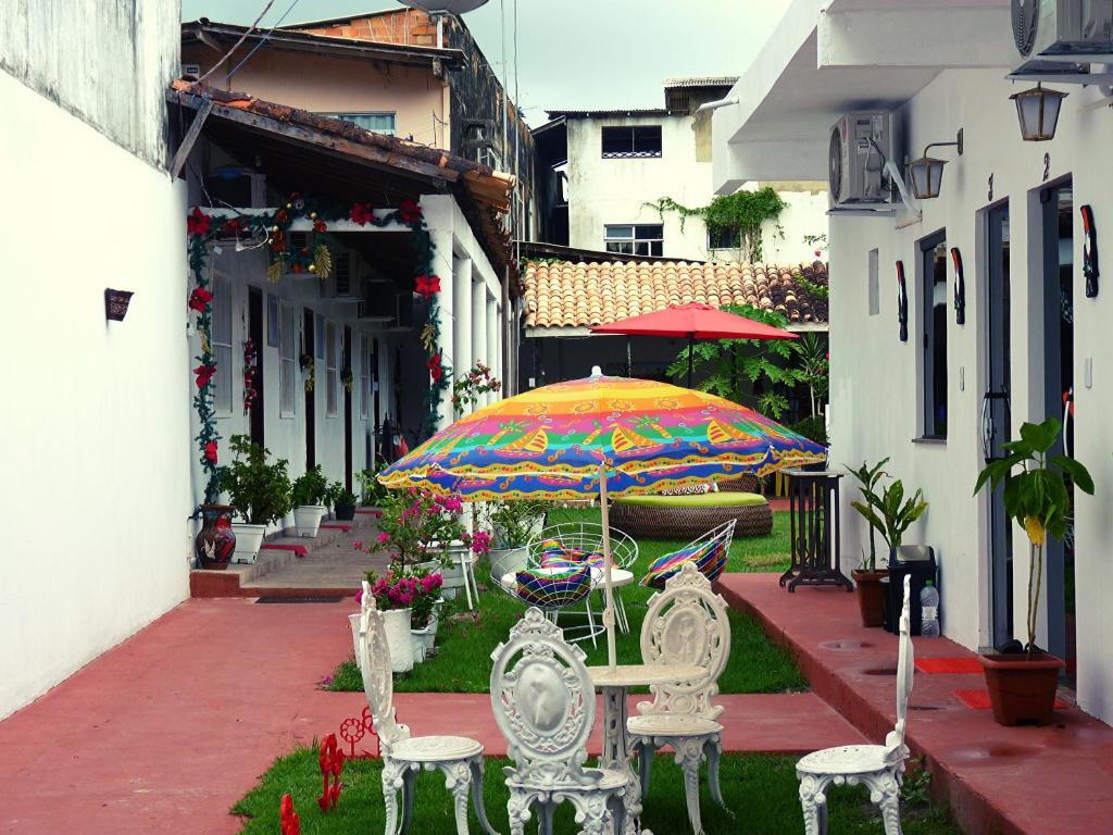 um pátio com mesas e cadeiras e um guarda-sol em Pousada Solar Encanto do Marajó em Soure