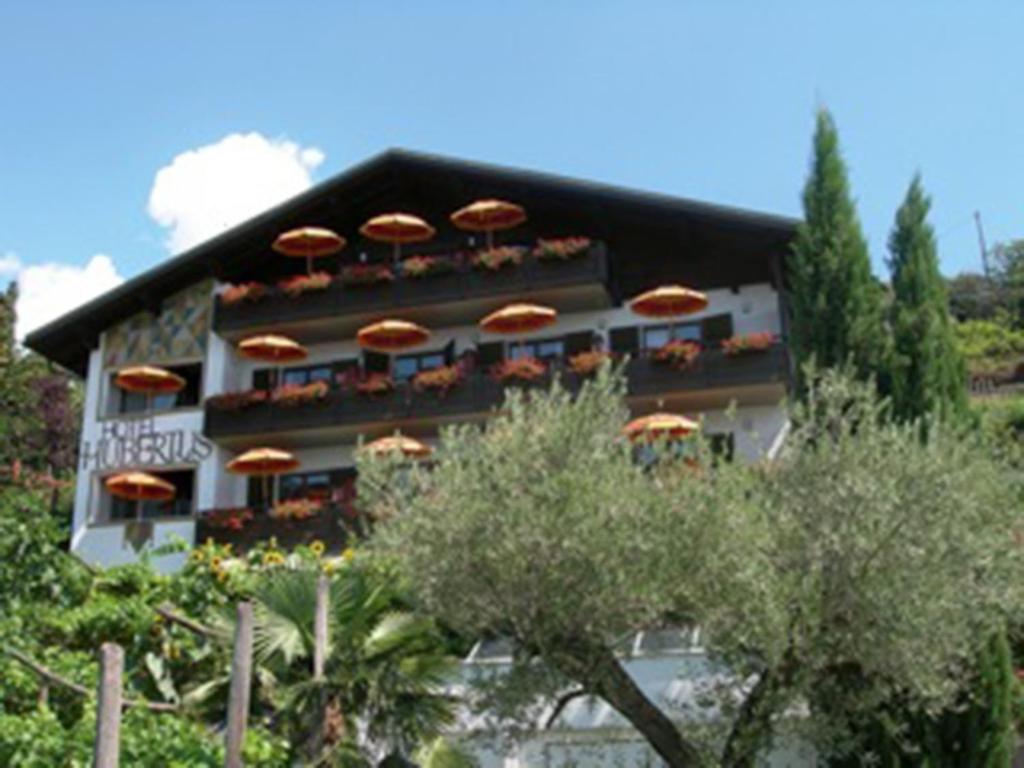 ein Gebäude mit orangefarbenen Sonnenschirmen darüber in der Unterkunft Hotel Garni Hubertus in Dorf Tirol