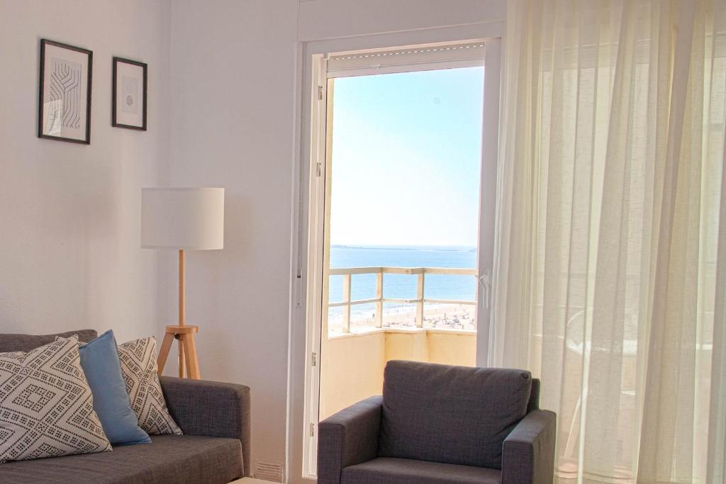 uma sala de estar com uma cadeira e vista para o oceano em Sunset Victoria Beach em Cádiz
