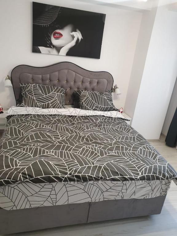 a bed with a black and white comforter and pillows at Topaz Central Apartment in Bacău