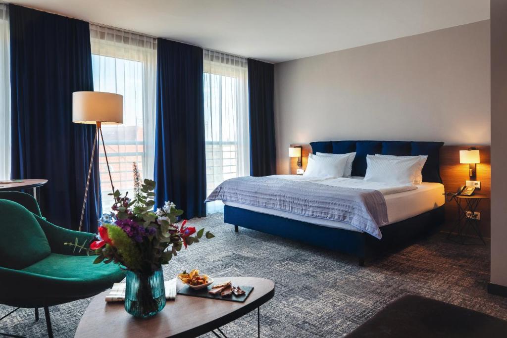a hotel room with a bed and a green chair at Holiday Inn Berlin City Center East Prenzlauer Berg by IHG in Berlin