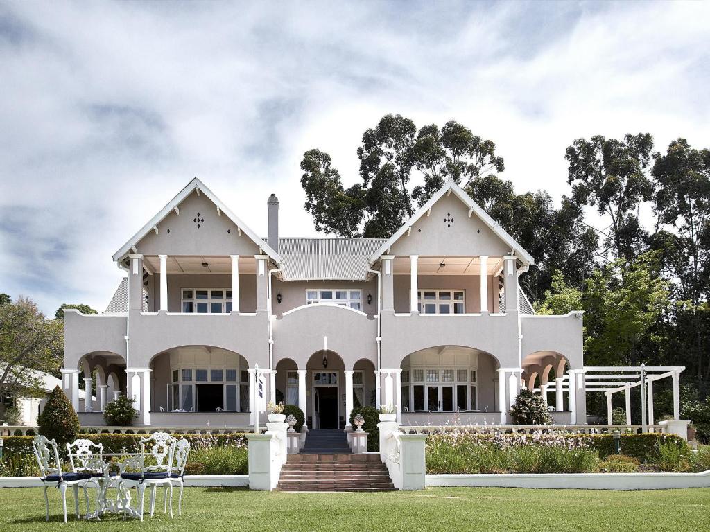 a large white house with chairs on the lawn at Parkes Manor in Knysna
