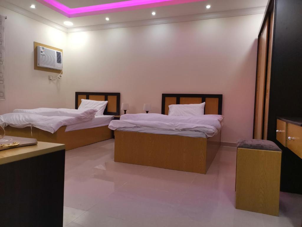 two beds in a room with purple lighting at Al Shadi Apartment Private Tourism in Yanbu