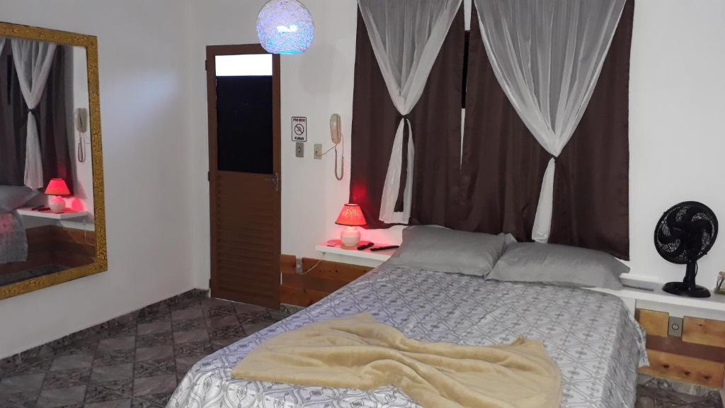sypialnia z łóżkiem i dużym lustrem w obiekcie Pousada São Pedro w mieście Lambari