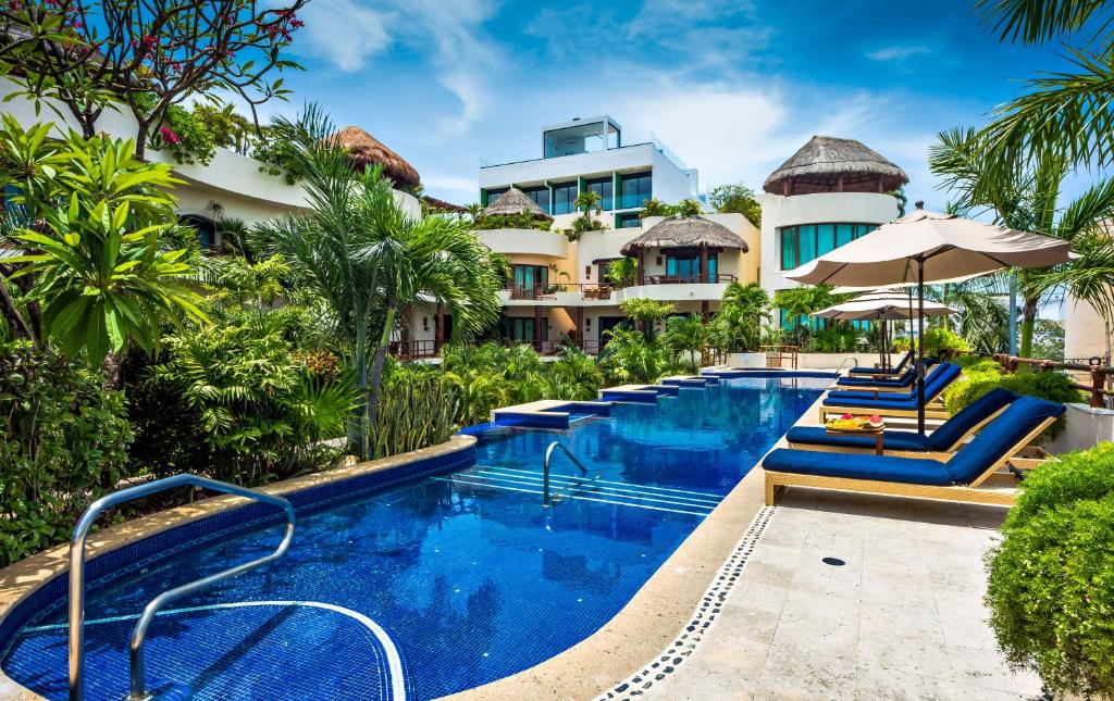 a resort with a swimming pool and a building at Porto Playa Condo Hotel and Beach Club in Playa del Carmen