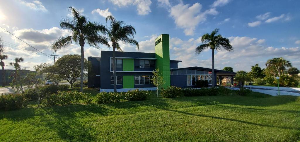 a house with palm trees in front of a yard at Travel Inn Fort Pierce in Fort Pierce