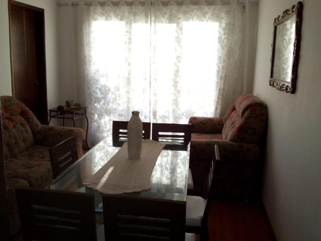 a living room with a table and chairs and a window at CASANOGh NOVO TEMPO in Curitiba