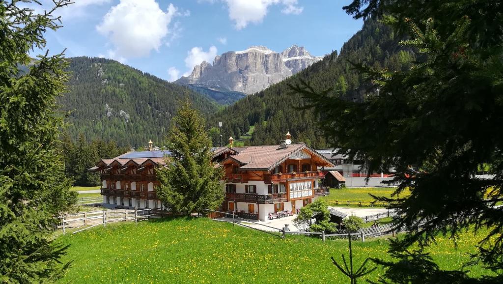 a house in a field with a mountain in the background at Appartamenti Agriturismo Cèsa Ciasates in Canazei