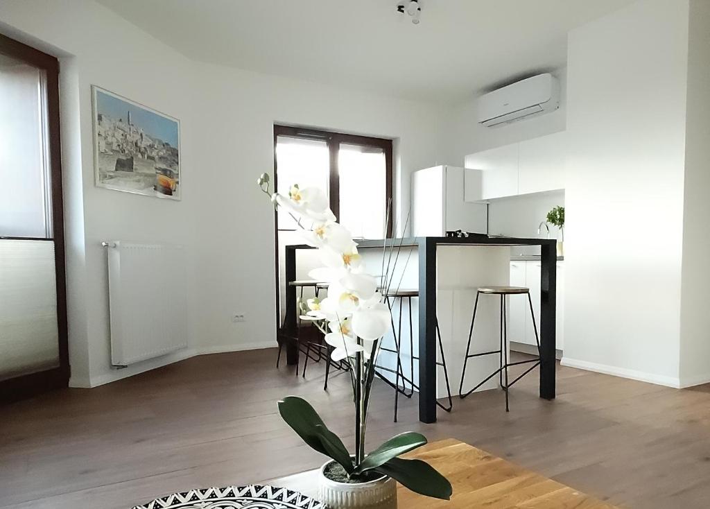 a living room with a kitchen and a table with white flowers at Central Port Warsaw Apartment in Warsaw